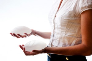 woman holding two breast implants